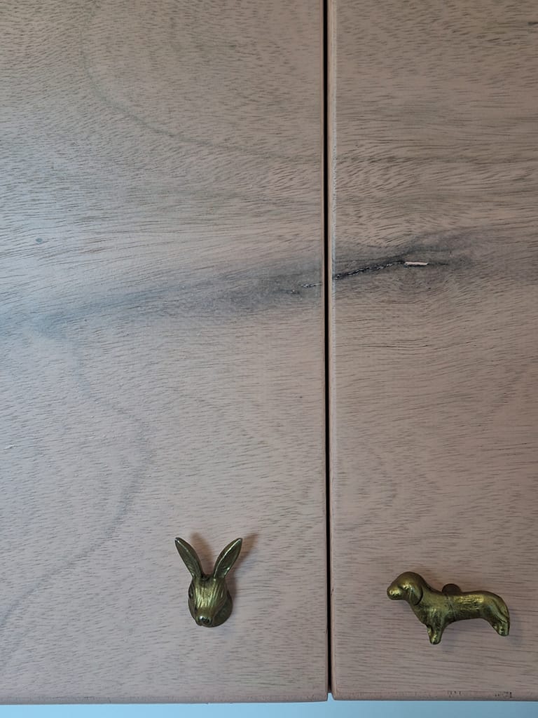 detail houten kastdeur met gouden dierenknoppen.