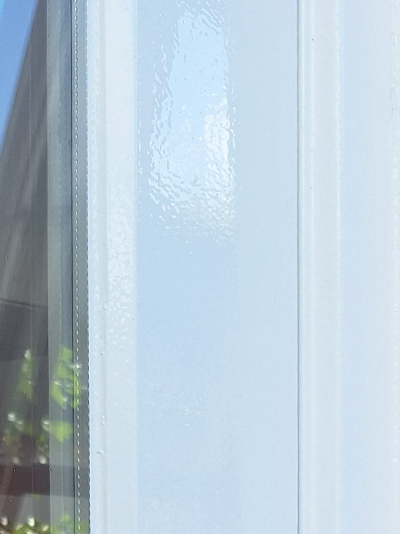 detail foto van kozijn met een strakke lijn langs het glas en een, extreem glimmend, hoogglans wit kozijn.